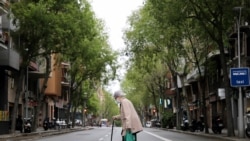 Una persona mayor cruza una calle de Barcelona tras ir a comprar al supermercado, una de las pocas cosas permitidas durante el confinamiento obligatorio.