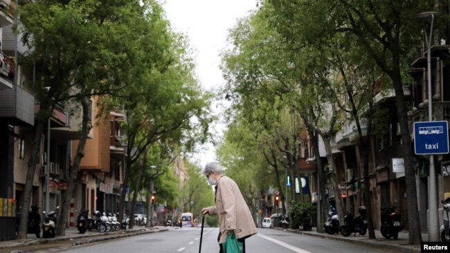 Una persona mayor cruza una calle de Barcelona tras ir a comprar al supermercado, una de las pocas cosas permitidas durante el confinamiento obligatorio.