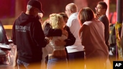 People comfort each other as they stand near the scene, Nov. 8, 2018, in Thousand Oaks, Calif. where a gunman opened fire Wednesday inside a country dance bar crowded with hundreds of people.