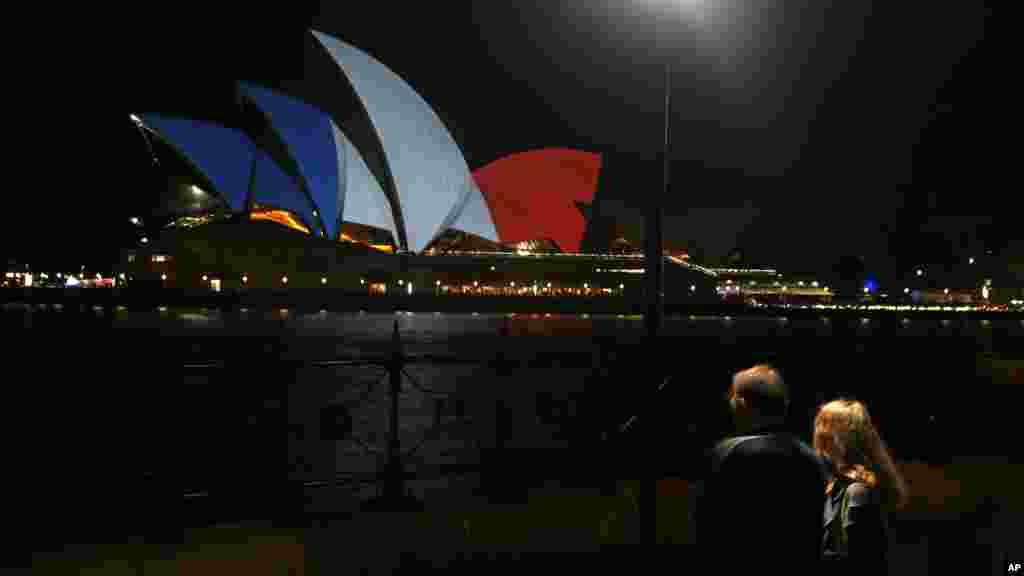 A couple look at the sails of the Sydney Opera House that are lit in the colors of the French flag in Sydney, following the terrorist attacks in Paris, Nov. 14, 2015.