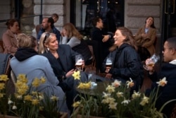 FILE - In this Wednesday, April 8, 2020 file photo people chat and drink outside a bar in Stockholm, Sweden. Sweden is pursuing relatively liberal policies to fight the coronavirus pandemic, even though there has been a sharp spike in deaths. (AP Photo/An