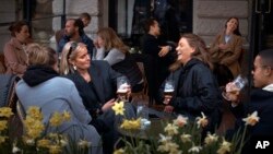 FILE - In this Wednesday, April 8, 2020 file photo people chat and drink outside a bar in Stockholm, Sweden. Sweden is pursuing relatively liberal policies to fight the coronavirus pandemic, even though there has been a sharp spike in deaths. (AP Photo/An