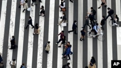 FILE - People walk in the Ginza shopping district in Tokyo, March 31, 2023. A report issued Wednesday by the Organization for Economic Cooperation and Development predicts Japan's economy is on pace to go from a decline of 0.1% this year to 1.4% growth in 2025.