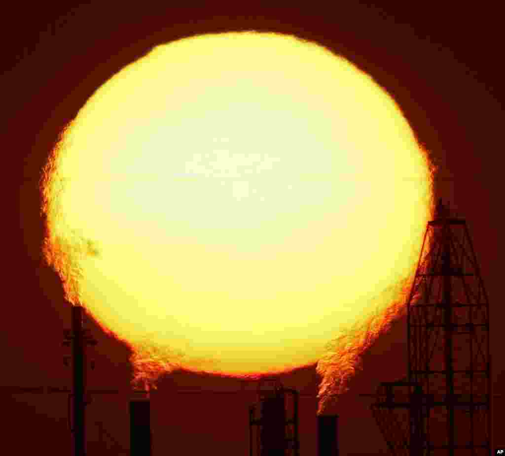 Matahari tenggelam di balik kilang minyak National Cooperative Refinery Association di McPherson, Kansas, USA, 19 Agustus 2015.