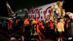 La policía vigila el área mientras rescatistas y bomberos rodean los restos del avión accidentado en la pista del aeropuerto Sabiha de Estambul, Turquía, el 5 de febrero de 2020.