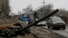 Empty buses wait along a road beside a burnt-out tank turret while travelling in the direction of Debaltseve to evacuate the residents, in Vuhlehirsk, Donetsk region, Feb. 6, 2015.