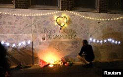 A man reads messages of condolence on a wall near a tower block severely damaged by a serious fire, in north Kensington, West London, June 15, 2017.