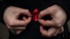 A woman adjusts a red ribbon, symbol of the fight against AIDS during a demonstration on World AIDS Day, Dec. 1, 2014.