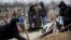 Relatives of Vitaliy Sirotenko, a victim of Saturday's shelling, stand near a grave during funerals in Mariupol, Ukraine, Jan. 27, 2015.