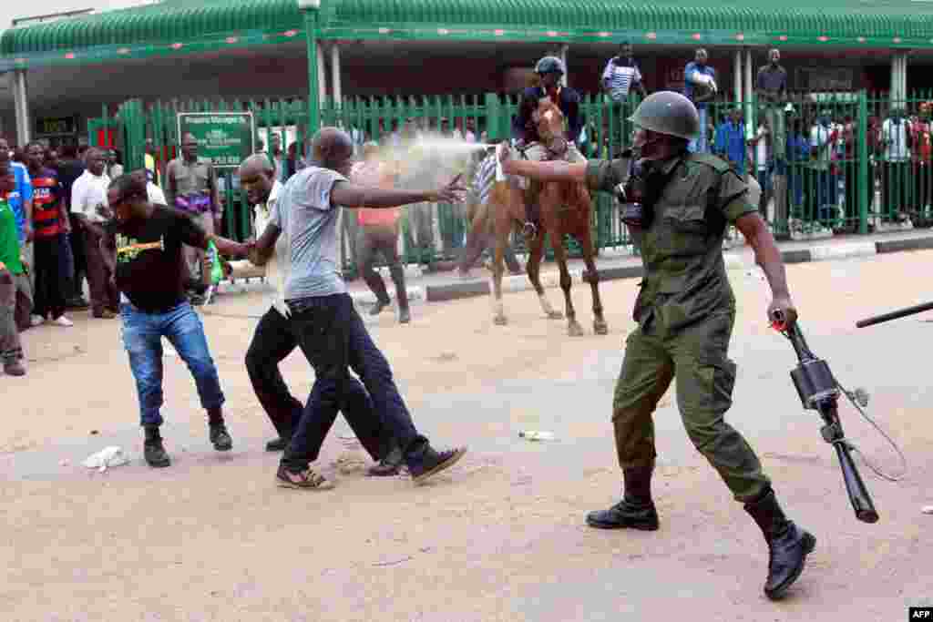 یک پلیس اوگاندایی به معترضان اسپری فلفل می زند.
