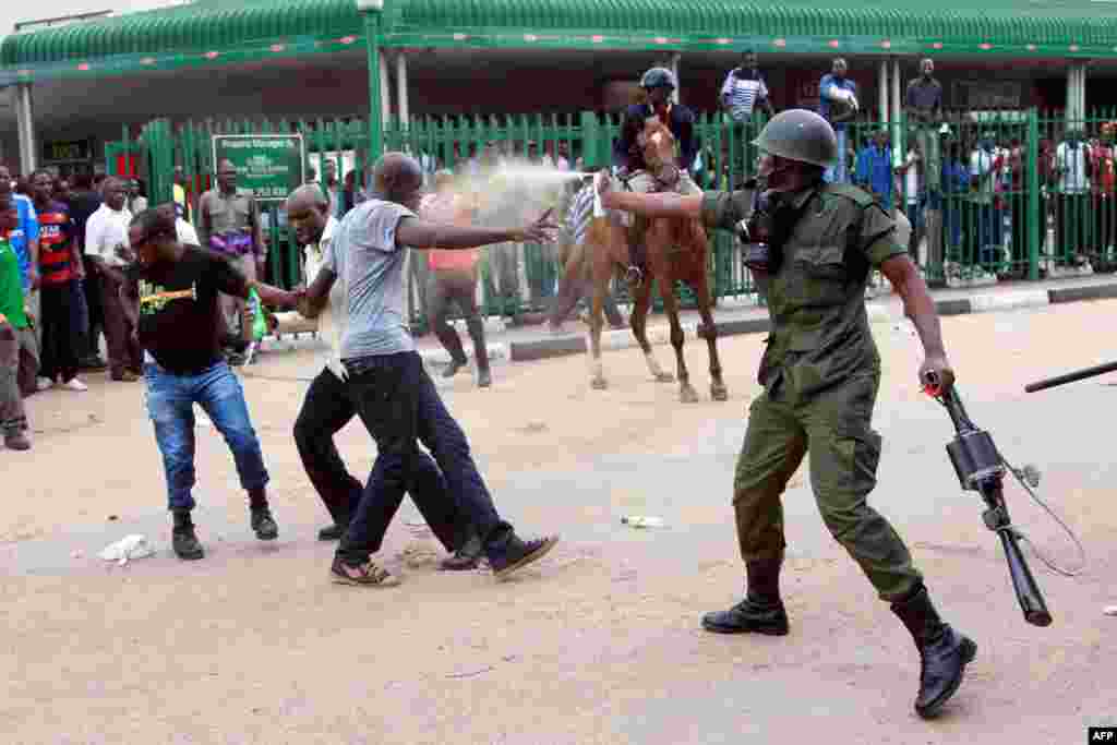 A policeman fires pepper spray toward supporters of the opposition United Party for National Development (UPND) outside the Woodlands Police Station in Lusaka, Uganda.