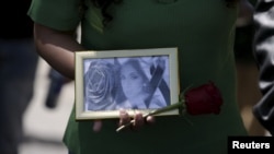 FILE - A picture of Andrea Alvarez, whose death is being investigated as a femicide, is displayed during a rally at her funeral march in La Paz, Bolivia, Aug. 22, 2015. 