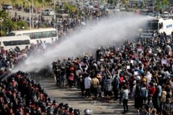 FILE - Police fire a water cannon at protesters demonstrating against the coup and demanding the release of elected leader Aung San Suu Kyi, in Naypyitaw, Myanmar, Feb. 8, 2021.