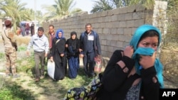 Iraqi pro-governement forces help people displaced from Islamic State (IS) group controlled areas close to Fallujah, on February 7, 2016.