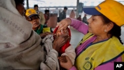 A medical volunteer administers polio immunization drops to a child at a railway station in Allahabad, India, Jan. 13, 2014.