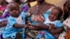 (FILE) Dorcas Simon, 38-year-old, plays with her twin daughters during a food training event in Kaltungo's Poshereng Nigeria, Sunday, June 2, 2024.