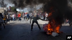 A protester burns a picture of Haiti's President Michel Martelly as demonstrators call for Martelly's departure from office on the anniversary of the Vertières battle in Port-au-Prince, Nov. 18, 2013.