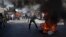 A protester burns a picture of Haiti's President Michel Martelly as demonstrators call for Martelly's departure from office on the anniversary of the Vertières battle in Port-au-Prince, Nov. 18, 2013.