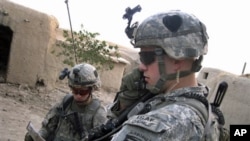 Soldiers from the US 101st Airborne Division's 1st Battalion, 5 Lt. Cory Donohoo, right, makes a radio call while Pfc. Michael Miles reads a map as troops search a home in Senjeray, Kandahar province, Afghanistan, 7 Sept. 2010.