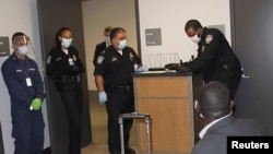 FILE - U.S. Customs and Border Protection officers screen a traveler who had recently visited Guinea at Atlanta's international airport, Oct. 16, 2014.