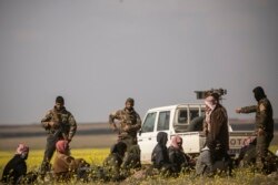 FILE - Men suspected of being Islamic State fighters arrive at a screening point run by U.S.-backed Syrian Democratic Forces, where suspected jihadists were being interrogated outside Baghuz in Syria, March 6, 2019.