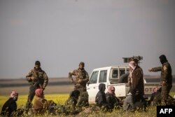 FILE - Men suspected of being Islamic State fighters arrive at a screening point run by U.S.-backed Syrian Democratic Forces, where suspected jihadists were being interrogated outside Baghuz in Syria, March 6, 2019.