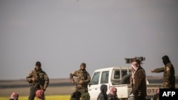FILE - Men suspected of being Islamic State fighters arrive at a screening point run by Syrian Democratic Forces, outside Baghuz, Syria, March 6, 2019.