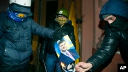 Manifestantes queman un retrato del presidente ucraniano, Viktor Yanukovych, a la entrada del ministerio de Justicia.