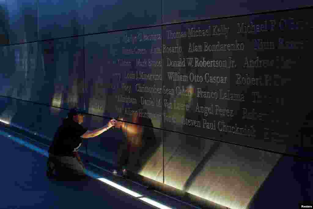 Seorang warga yang berduka menempatkan bendera di memorial Empty Sky di New Jersey (11/9). (Reuters/Andrew Kelly)