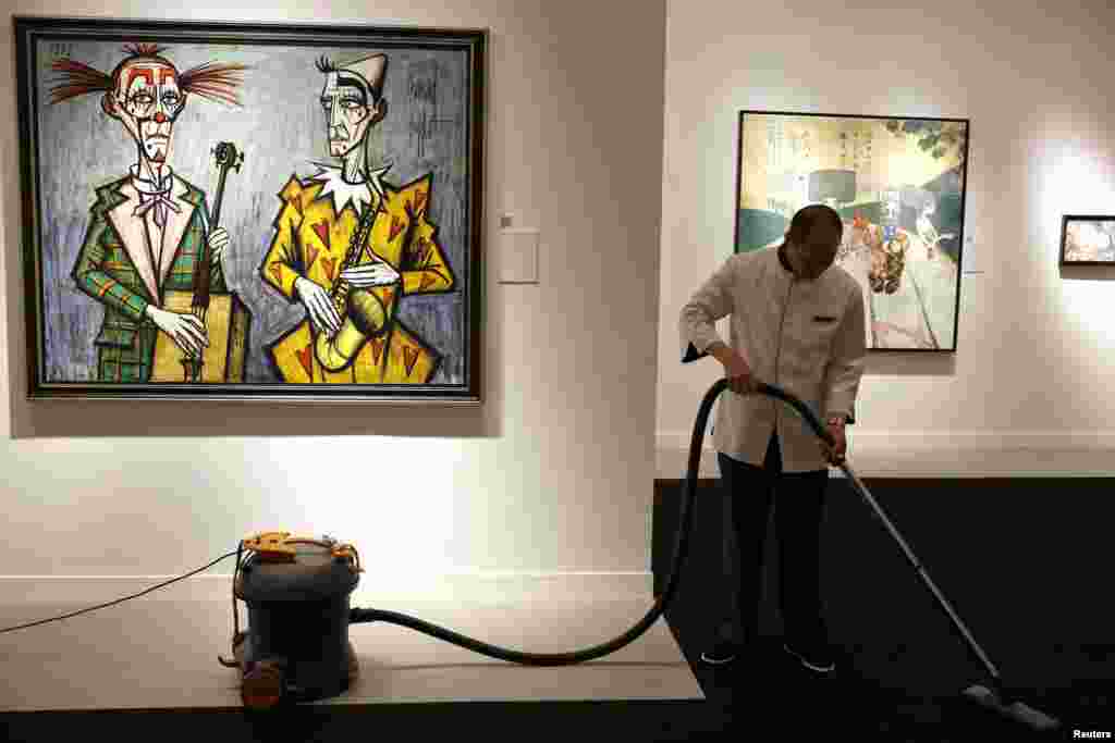 An employee vacuums the carpet next to Bernard Buffet&#39;s &quot;Deux clowns, saxophone&quot; during a media preview of Christie&#39;s Shanghai Spring Auction in China. Christie&#39;s will present the auction on April 26.