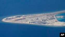 菲律宾空军一架运输机在南中国海南沙群岛的中国造的人造岛礁渚碧礁上空飞越时拍摄的照片，显示人造岛礁上的简易机场和建筑物。（2017年4月21日） 
