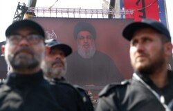 FILE - Hezbollah security forces stand guard as their leader Sheik Hassan Nasrallah speaks via a video link on a screen in the southern suburb of Beirut, Lebanon, Sept. 10, 2019.