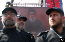 FILE - Hezbollah security forces stand guard as their leader Sheik Hassan Nasrallah speaks via a video link on a screen in the southern suburb of Beirut, Lebanon, Sept. 10, 2019.