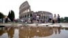 FILE - Tourists walk by the ancient Roman Colosseum as it's reflected in a puddle, in Rome, Sept. 5, 2024. 