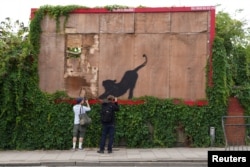 FILE - A person takes pictures of the new artwork of a cat, by the British artist Banksy, on Edgware Road, in London, Britain, August 10, 2024. REUTERS/Maja Smiejkowska