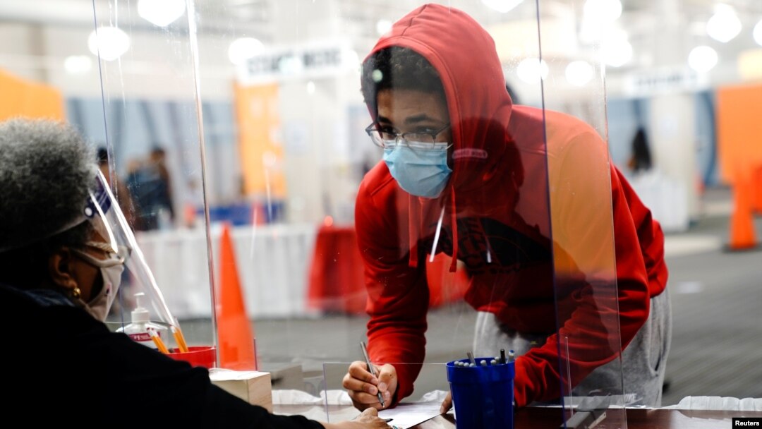 Seorang pemilih muda mengisi surat suara dibantu oleh petugas pemungutan suara di tempat pemungutan suara di mal Midtown Center, Milwaukee, pada hari pertama pencoblosan langsung, di Wisconsin, 20 Oktober 2020. (Foto: Reuters) 