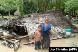 Une vielle femme et son petit-fils se tiennent devant leur maison endommagée dans le village de Haitimuk, dans l'est de Flores, le 4 avril 2021.