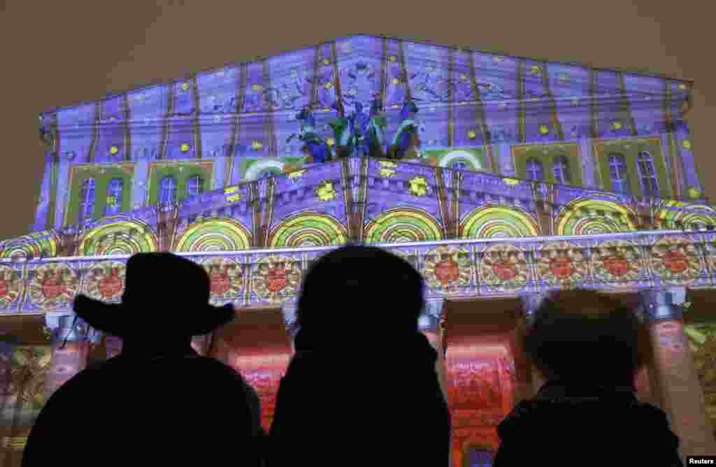 People look at a light installation during the &quot;City of Angels&quot; show based on Russian ornamental and fine arts, at the Bolshoi Theatre building in Moscow.