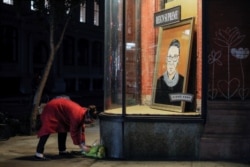 A person places flowers in front of a painting in a storefront on Broadway of Associate Justice of the Supreme Court of the United States Ruth Bader Ginsburg who passed away in Manhattan, New York City, U.S., September 18, 2020. REUTERS/Andrew Kelly