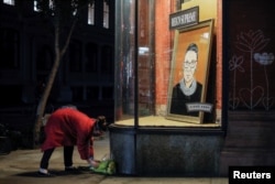 A person places flowers in front of a painting in a storefront on Broadway of Associate Justice of the Supreme Court of the United States Ruth Bader Ginsburg who passed away in Manhattan, New York City, U.S., September 18, 2020. REUTERS/Andrew Kelly