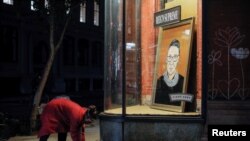 A person places flowers in front of a painting in a storefront on Broadway of Associate Justice of the Supreme Court of the United States Ruth Bader Ginsburg who passed away in Manhattan, New York City, U.S., September 18, 2020.
