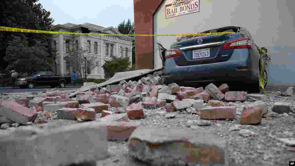 Bricks and fallen rubble cover a car with the old courthouse in the background following an earthquake in Napa, California, Aug. 24, 2014.