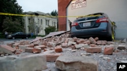 Bricks and fallen rubble cover a car with the old courthouse in the background following an earthquake in Napa, California, Aug. 24, 2014.