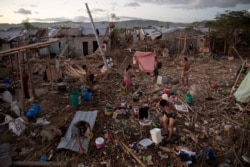 Residents bathe, wash, and pump water in their destroyed village following the damage caused by Typhoon Vamco, in Rodriguez, Rizal province, Philippines.