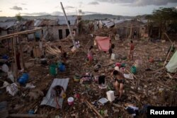 Residents bathe, wash, and pump water in their destroyed village following the damage caused by Typhoon Vamco, in Rodriguez, Rizal province, Philippines.
