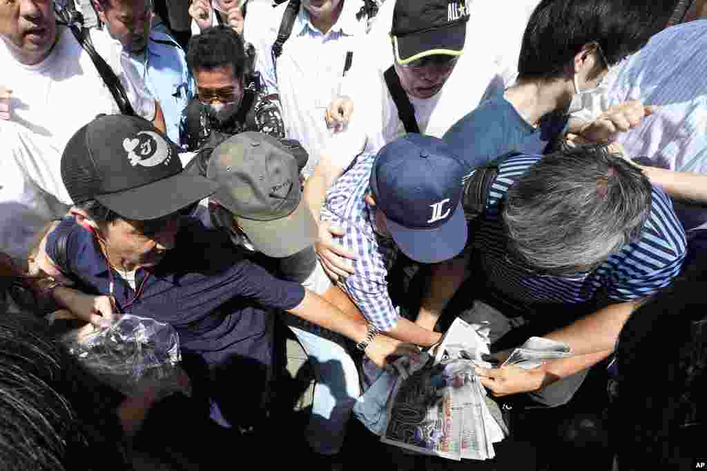 Pedestrians try to obtain an extra edition of the Sports Hochi newspaper reporting on the Los Angeles Dodgers' Shohei Ohtani becoming the first player in major league history with 50 home runs and 50 stolen bases in a season, in Tokyo. 