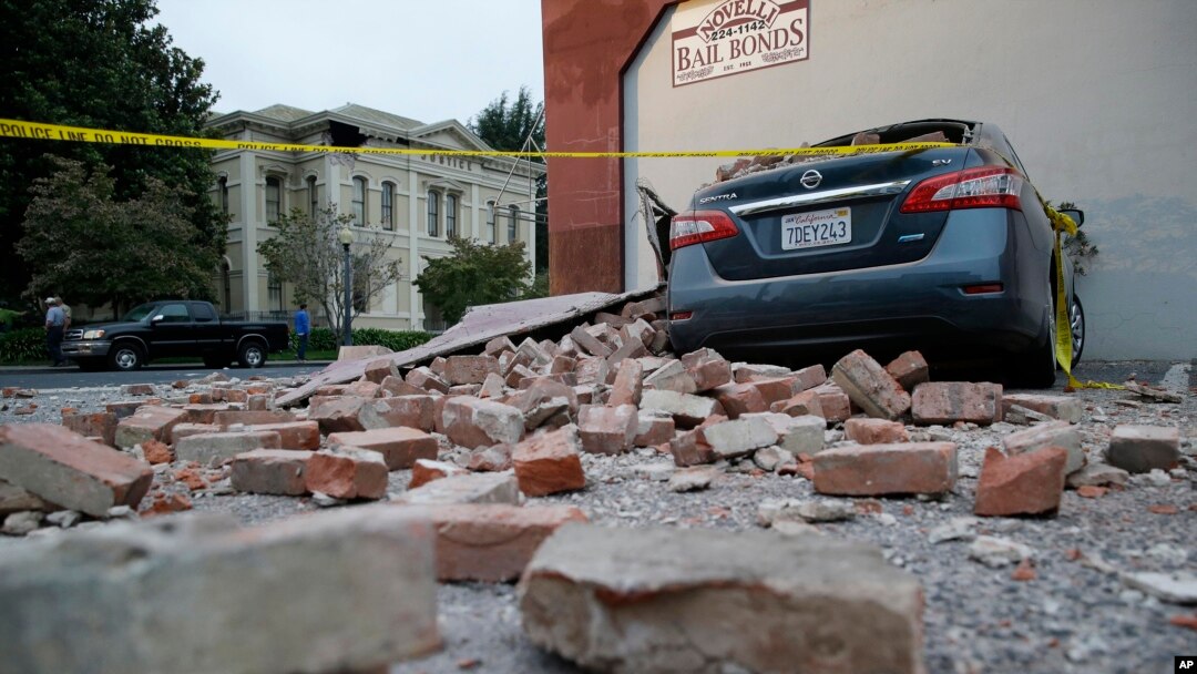 Bricks and fallen rubble cover a car with the old courthouse in the background following an earthquake in Napa, California, Aug. 24, 2014.