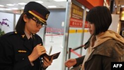 An airport security officer (L) checks a passenger's passport and boarding pass at Taipei Songshan Airport on March 10, 2014. 