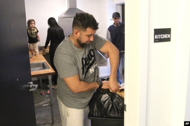 Javier Chirinos Mendoza takes out a garbage bag from the communal kitchen in a 'micro apartment' building in Seattle on Monday, March 11, 2024. (AP Photo/Manuel Valdes)