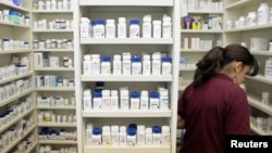 FILE - A pharmacy employee looks for medication as she works to fill a prescription.